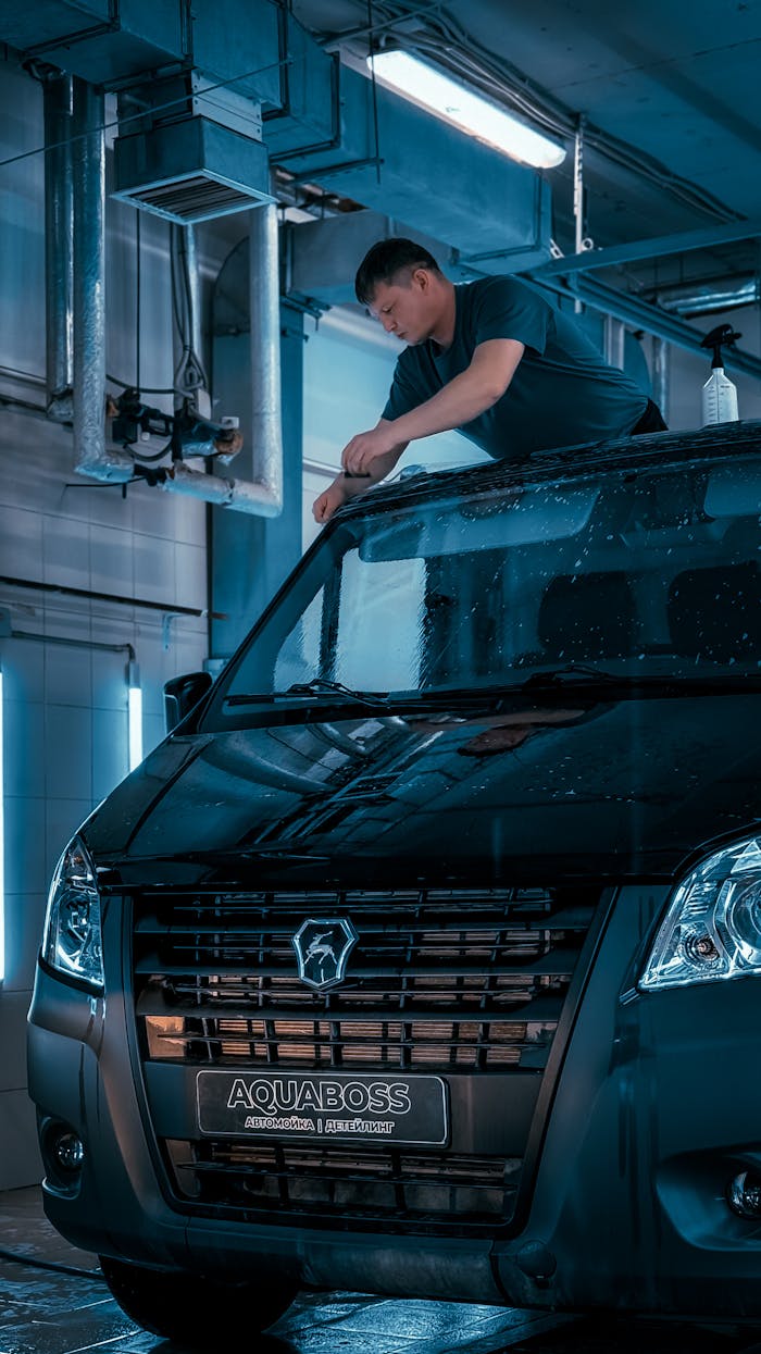 A man cleaning a black van in an indoor car wash, highlighting automotive service.